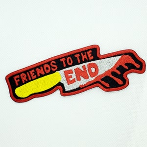 以下が含まれることがあります： ナイフと「Friends to the End」という文字が刺繍された赤と黒のパッチです。