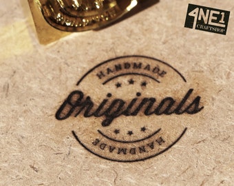 Könnte beinhalten: Ein schwarzer und weißer runder Stempel mit dem Text "Handmade Originals Handmade" und drei Sternen. Der Stempel befindet sich auf einem braunen Papierhintergrund.