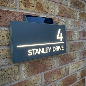 May include: A gray house number sign with white lettering. The sign reads "4 Stanley Drive".
