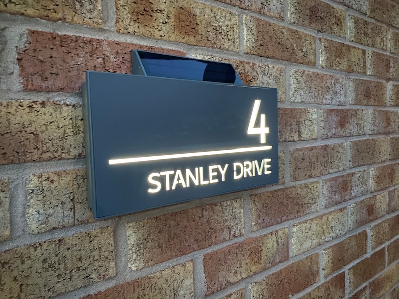 May include: A gray house number sign with white lettering. The sign reads "4 Stanley Drive".