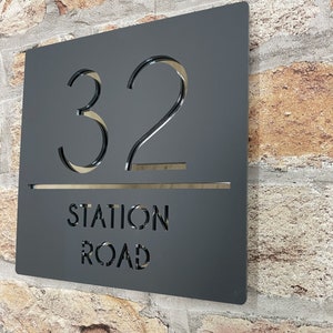 Puede incluir: Placa de n&uacute;mero de casa de metal negro con el n&uacute;mero 32 y el texto "STATION ROAD" recortado.