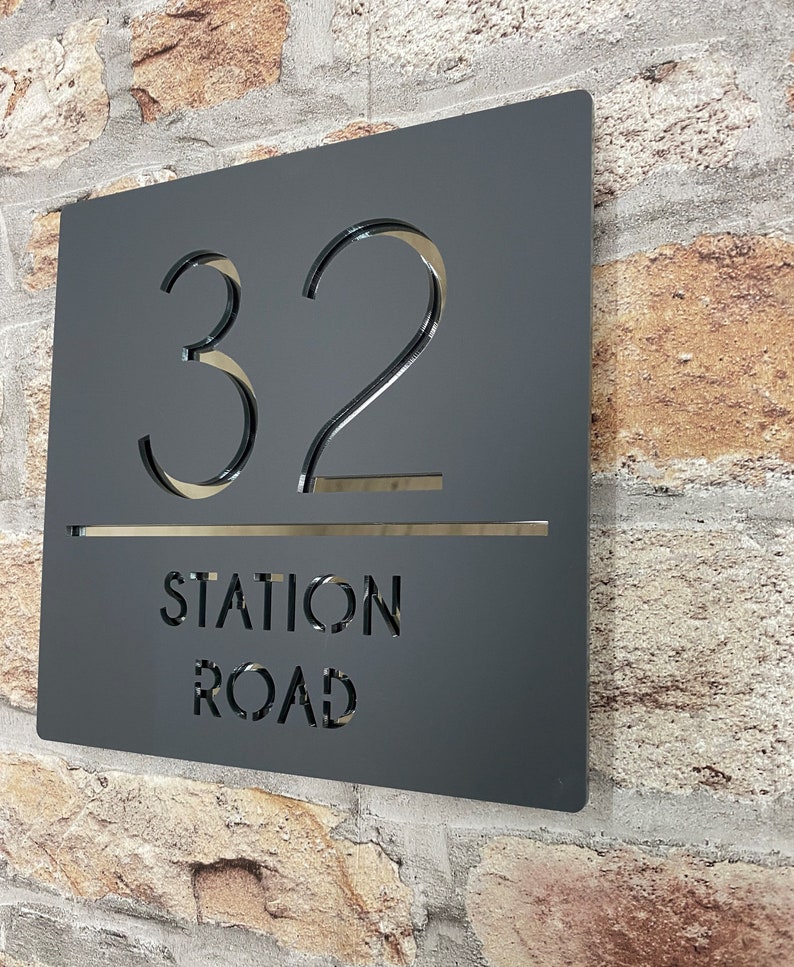 Puede incluir: Placa de n&uacute;mero de casa de metal negro con el n&uacute;mero 32 y el texto "STATION ROAD" recortado.