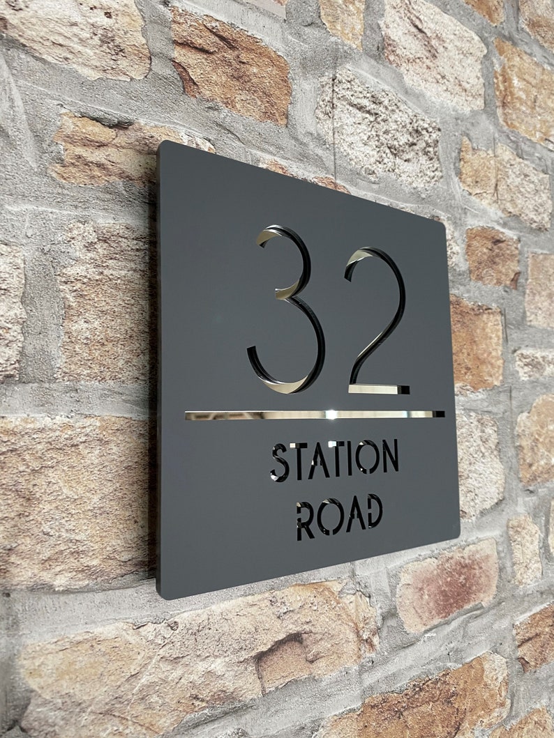 Puede incluir: Un letrero de n&uacute;mero de casa de metal negro con el n&uacute;mero 32 y el nombre de la calle "Station Road" recortado en blanco.