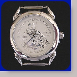 May include: A silver wristwatch with a silver band. The face of the watch features the American Eagle from the American Silver Eagle coin. The text on the face reads "United States of America", "E Pluribus Unum", "In God We Trust", and "$20 Dollars".