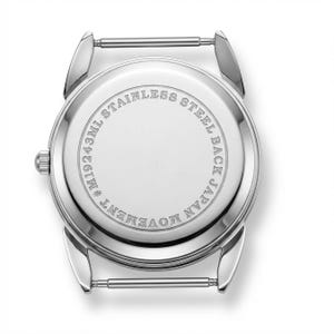 Może przedstawiać: Tył zegarka ze stali nierdzewnej z napisem "STAINLESS STEEL BACK JAPAN MOVEMENT" w okrągłym wzorze. Tył zegarka ma r&oacute;wnież napis "M19243ML". Zegarek ma srebrne uchwyty na pasek.