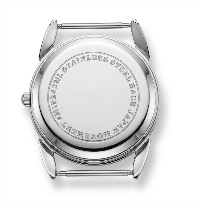 Może przedstawiać: Tył zegarka ze stali nierdzewnej z napisem "STAINLESS STEEL BACK JAPAN MOVEMENT" w okrągłym wzorze. Tył zegarka ma r&oacute;wnież napis "M19243ML". Zegarek ma srebrne uchwyty na pasek.