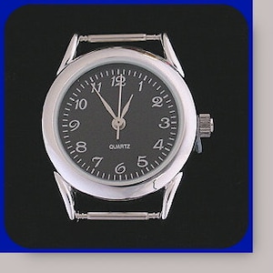 Könnte beinhalten: Eine silberne Uhr mit schwarzem Zifferblatt und schwarzen Zeigern. Die Uhr hat ein Quarzwerk und ein Armband.