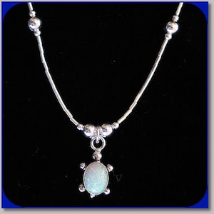 May include: A silver chain necklace with a silver turtle pendant featuring a white opal gemstone.