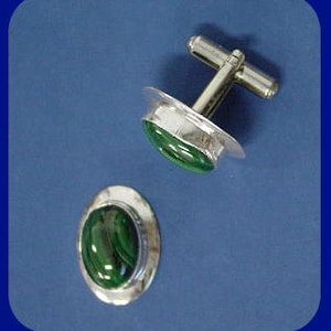 May include: A pair of silver cufflinks with oval-shaped green malachite stones.