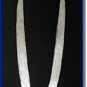 May include: A silver necklace made of many thin strands of metal. The necklace is long and hangs down to the chest.