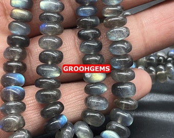 Puede incluir: Una hebra de cuentas de labradorita ovaladas de color gris oscuro con destellos iridiscentes azules y verdes. Las cuentas están enhebradas en un hilo transparente y tienen un diámetro aproximado de 8 mm.