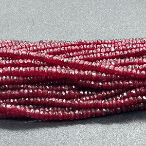 May include: A strand of deep red ruby beads, faceted and strung together. The beads are small and uniform in size, creating a smooth and elegant look.