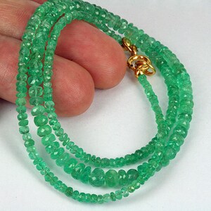 May include: A three-strand emerald green gemstone necklace with a gold clasp.