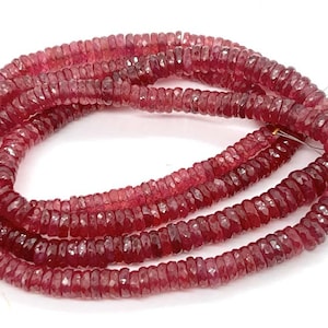 May include: A strand of pink ruby beads, faceted and round, strung on a wire. The beads are approximately 4mm in diameter and have a polished finish.