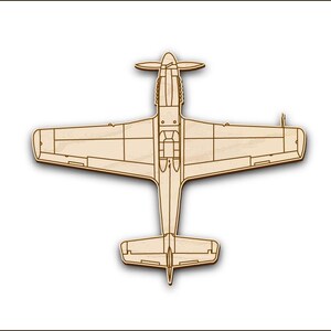 Peut inclure: Une découpe en bois d'un avion vintage, peut-être un P-51 Mustang, de couleur brun clair. L'avion est vu de dessus, montrant les ailes, le fuselage et la queue.