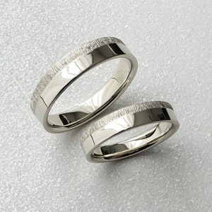 May include: Two silver wedding bands with a textured finish.