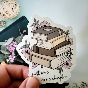 May include: A sticker with a stack of books, pink flowers, and the text "just one more chapter".