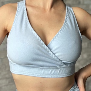 Op de afbeelding: Een lichtblauwe bralette in wikkelstijl met een V-hals. De bralette heeft gestikte randen en een gladde, naadloze uitstraling. De stof lijkt een lichtgewicht materiaal te zijn.