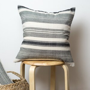 May include: Two black and white striped throw pillows, one on a wooden stool and one in a wicker basket.