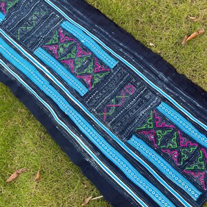 May include: A long piece of indigo blue fabric with white and blue stripes and intricate embroidered designs in pink, green, and white.