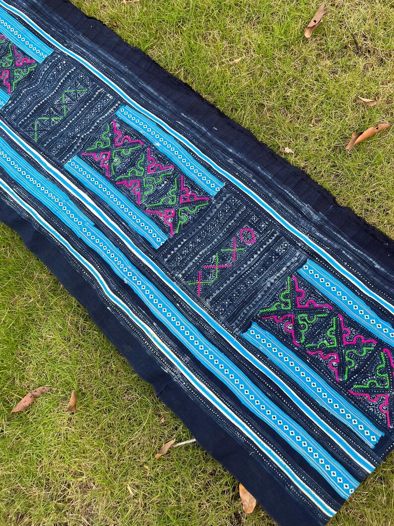 May include: A long piece of indigo blue fabric with white and blue stripes and intricate embroidered designs in pink, green, and white.