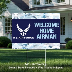 May include: A rectangular yard sign with a blue and white camouflage pattern. The sign features the U.S. Air Force logo and the words "WELCOME HOME AIRMAN" in white. The sign is 24 inches by 18 inches and is displayed on a metal stake.