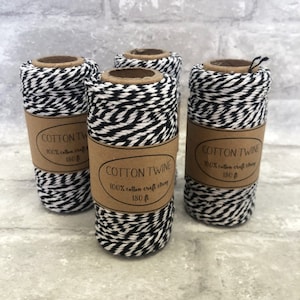 May include: Four spools of black and white striped cotton twine, each with a brown paper label that reads "COTTON TWINE 100% cotton craft string 180 ft."