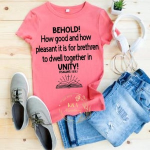 May include: Pink t-shirt with a black graphic that reads "BEHOLD! How good and how pleasant it is for brethren to dwell together in UNITY! PSALMS 133.1"