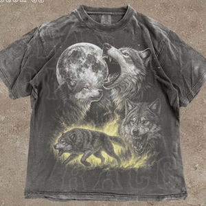 A t-shirt with a graphic design depicting three wolves howling at the moon, with a large full moon in the background.