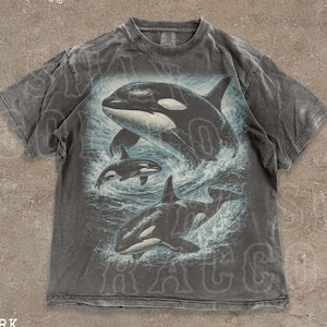 A grey t-shirt with a graphic design depicting two orca whales in the ocean.