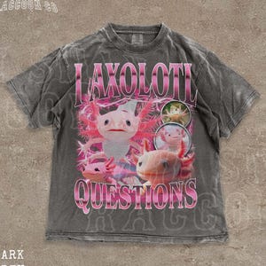 Könnte beinhalten: Dunkelgraues T-Shirt mit einer Grafik von Axolotln und dem Text "LAXOLOTL QUESTIONS". Das Design zeigt rosa und weiße Axolotl und rosa Text. Das T-Shirt hat einen Vintage-Look.