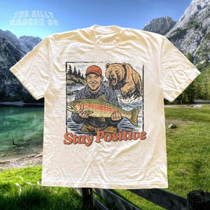 a t - shirt with a picture of a man holding a fish