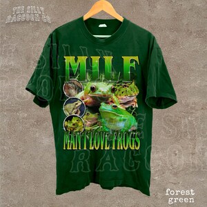 A green t-shirt with a graphic design featuring a frog and the text "MILF MAN I LOVE FROGS" printed on it.