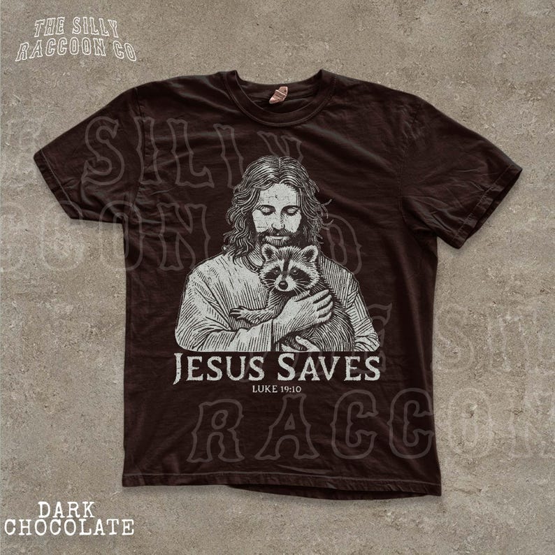 A t-shirt with a graphic design depicting a man holding a raccoon, along with the text "JESUS SAVES" and "LIKE YOURS".