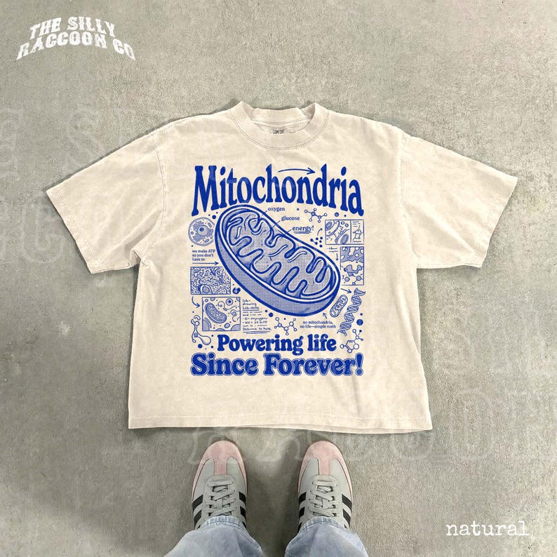 A white t-shirt with a graphic design featuring a Mitochondria-like structure and text, along with a pair of sneakers and a person's feet.
