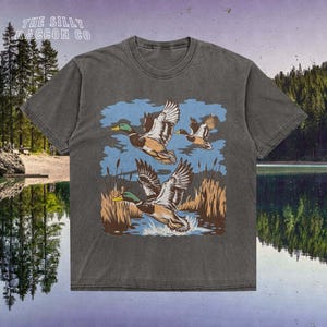 a t - shirt with ducks flying over a lake