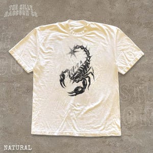 A white t-shirt with a black graphic of a scorpion printed on it.