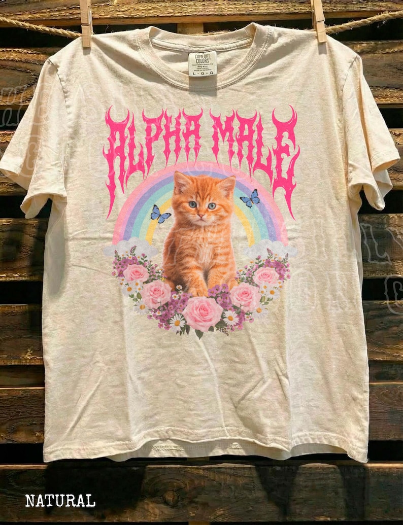 a white t-shirt with a graphic design of a cat surrounded by flowers and a rainbow.