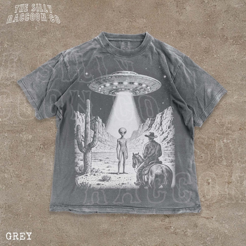 The image is a t-shirt design featuring a scene with an alien spacecraft hovering above a desert landscape, where a man on a horse is present.
