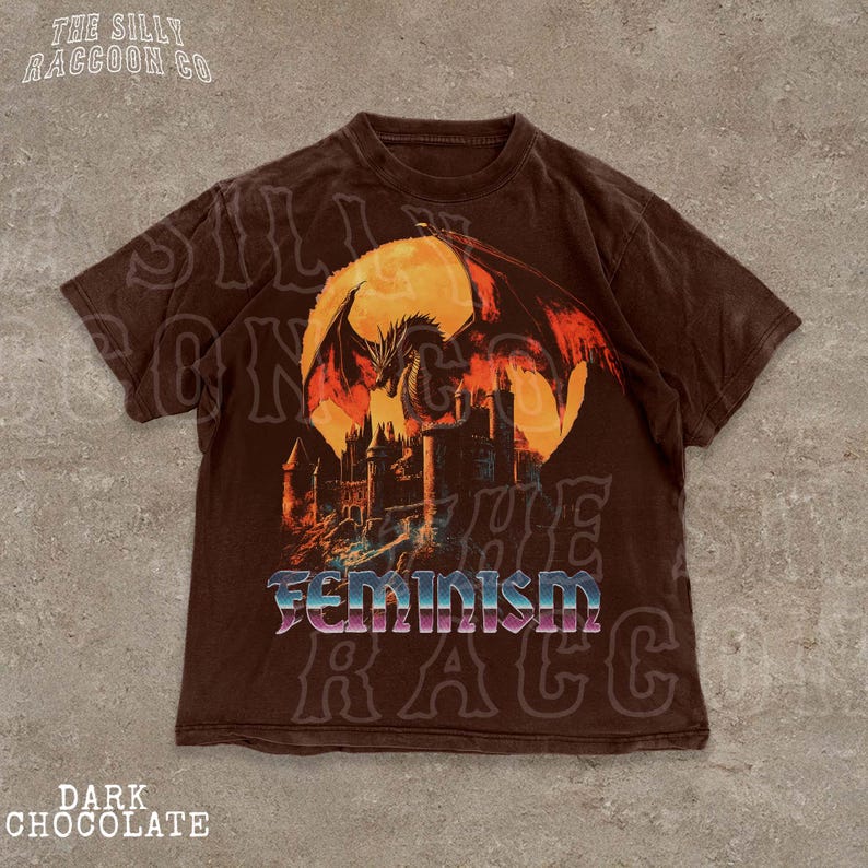 A brown t-shirt with a graphic design depicting a dragon and a castle, along with the word "Feminism" printed on it.