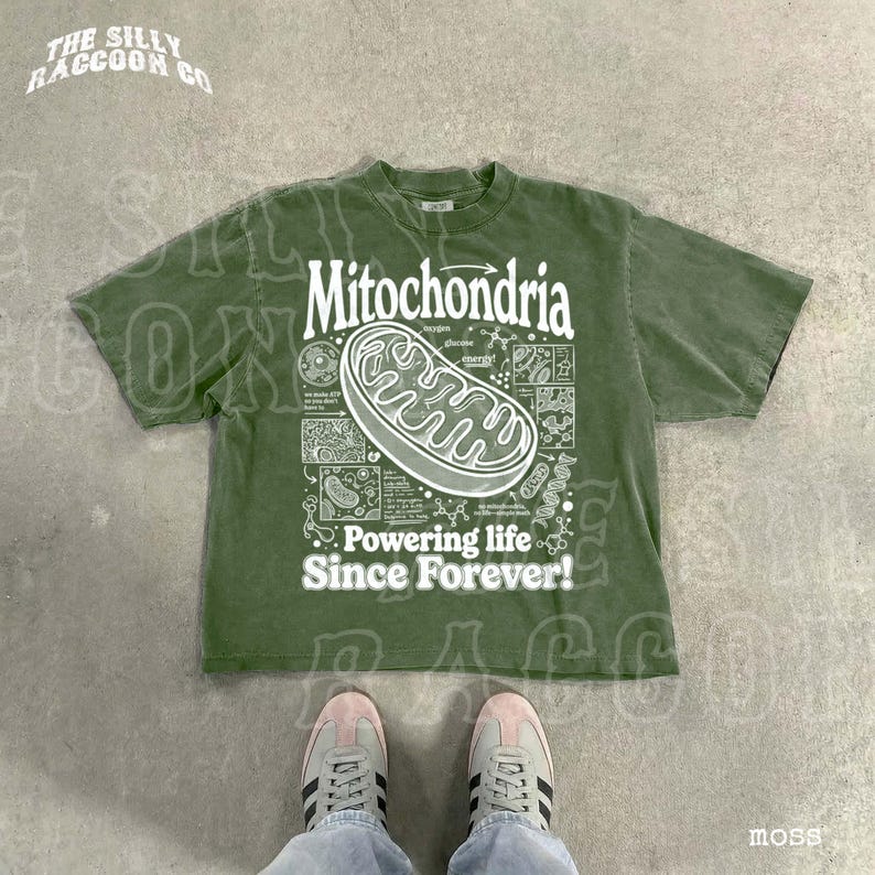 A pair of feet wearing a green t-shirt with a graphic design and text printed on it, placed on a concrete floor.