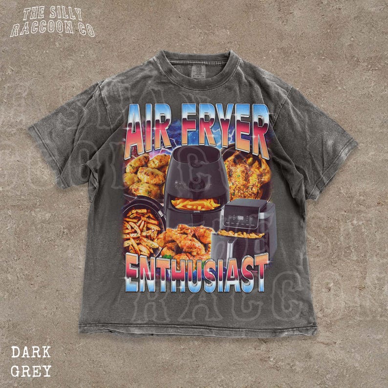 A t-shirt with a graphic design featuring an air fryer and various cooked food items, along with the text "AIR FRYER ENTHUSIAST" prominently displayed.