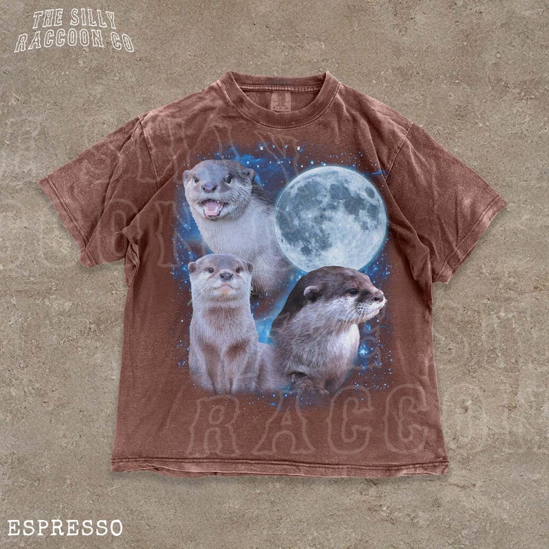 A brown t-shirt with a graphic design featuring three otters against a backdrop of a full moon and stars.
