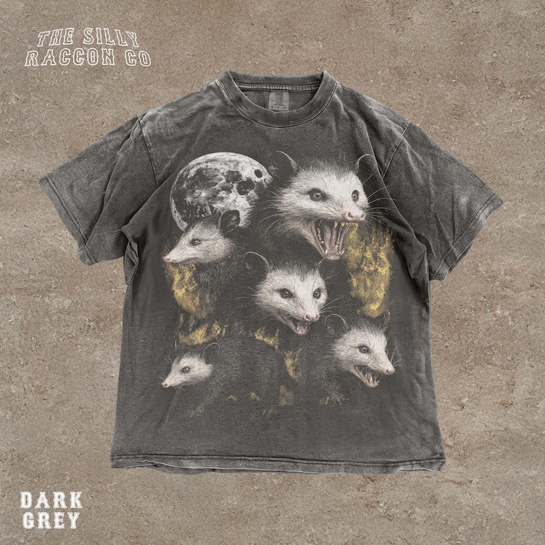 A t-shirt with a graphic design featuring multiple opossum faces with open mouths, arranged in a stacked formation.