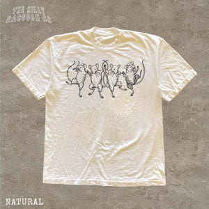 A white t-shirt with a black illustration of a group of cats or mice on it.