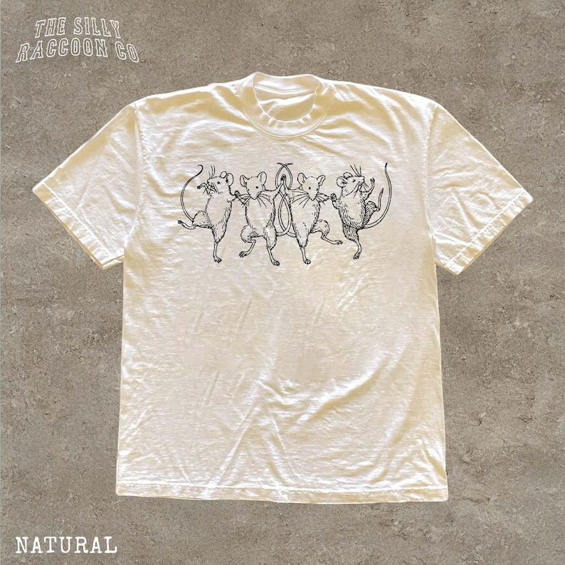 A white t-shirt with a black illustration of a group of cats or mice on it.