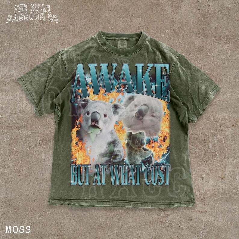 A t-shirt with a graphic design featuring two koalas and the text "AWAKES BUT AT WHAT COST" printed on it.