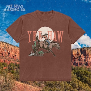 a t - shirt with a cowboy riding a horse in the desert