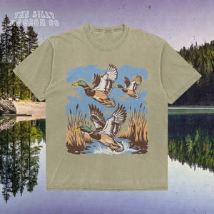 a t - shirt with two ducks flying over a lake