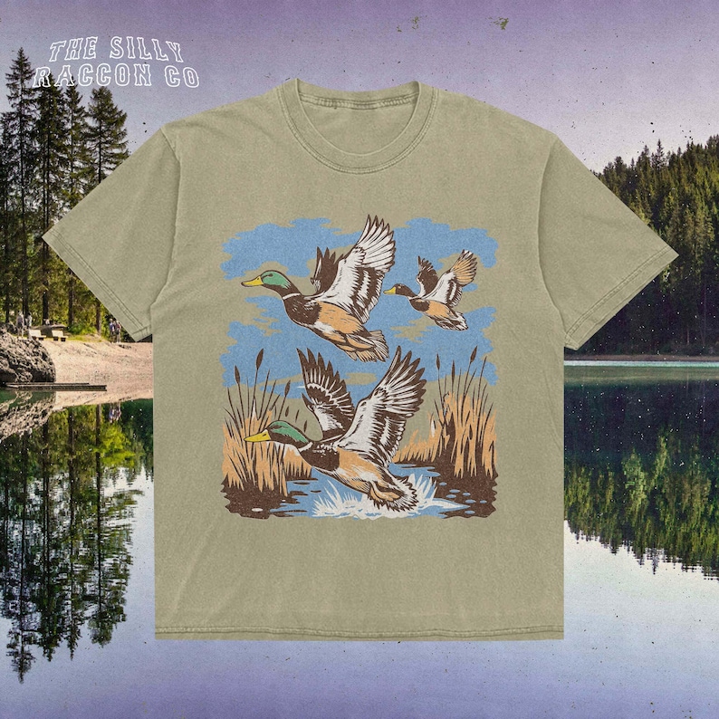 a t - shirt with two ducks flying over a lake